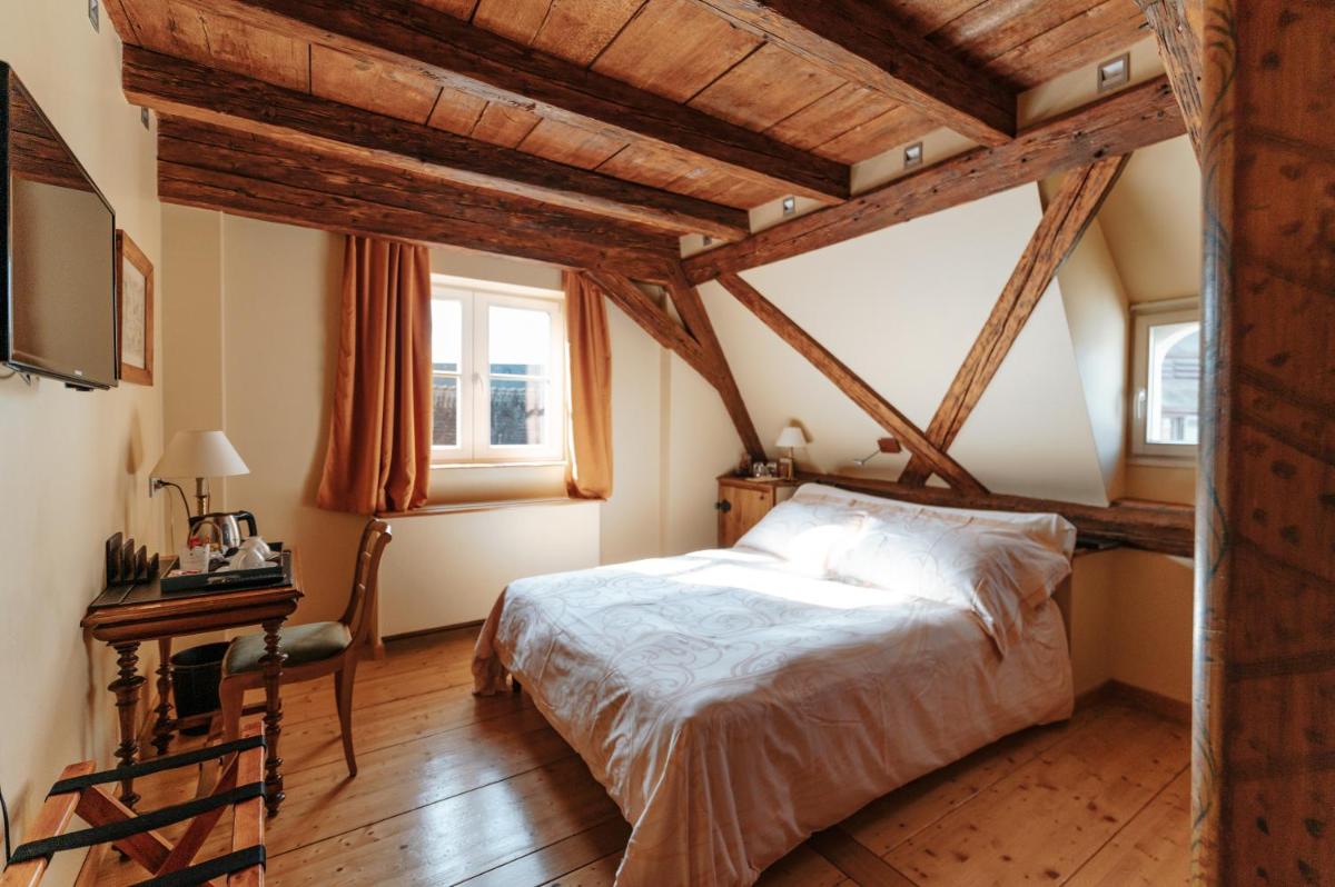 une chambre avec des plafonds en bois, un lit et une table dans l'établissement Hôtel & Spa Le Bouclier D'or, à Strasbourg
