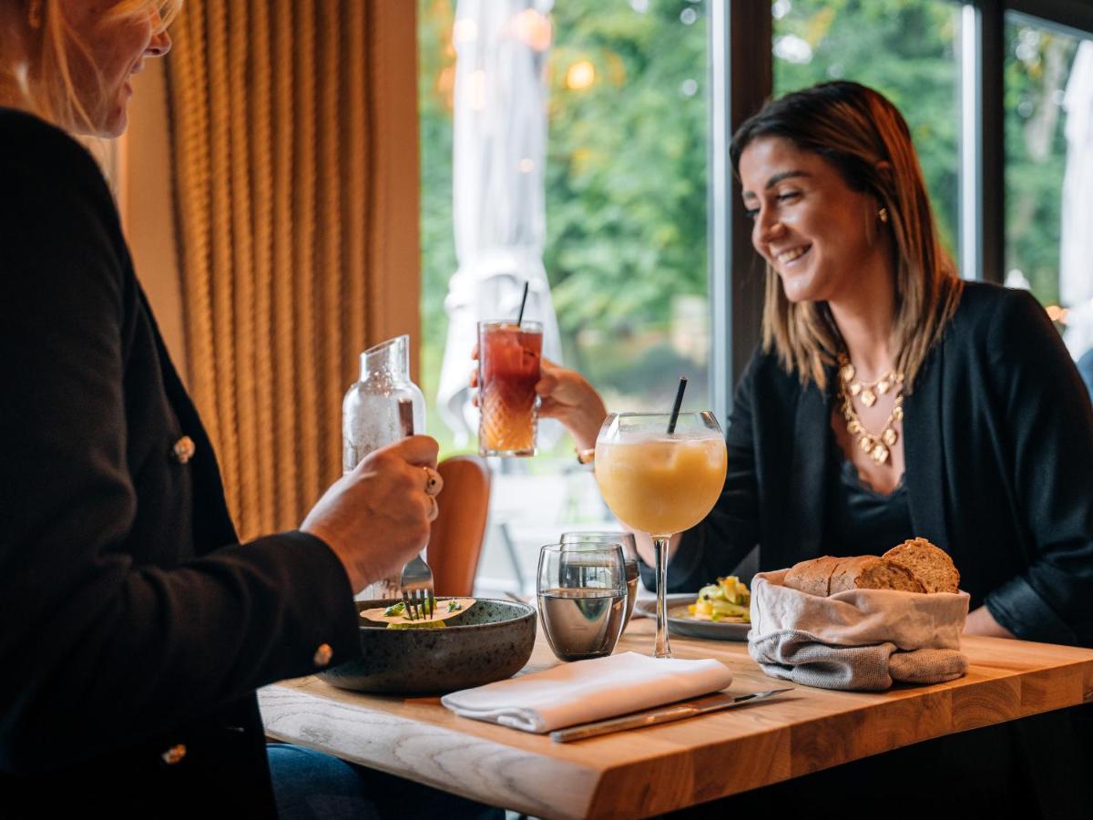 deux femmes assises à une table avec de la nourriture et des boissons dans l'établissement Domaine de Dolomieu Hotel & Spa - BW Premier Collection, à Dolomieux