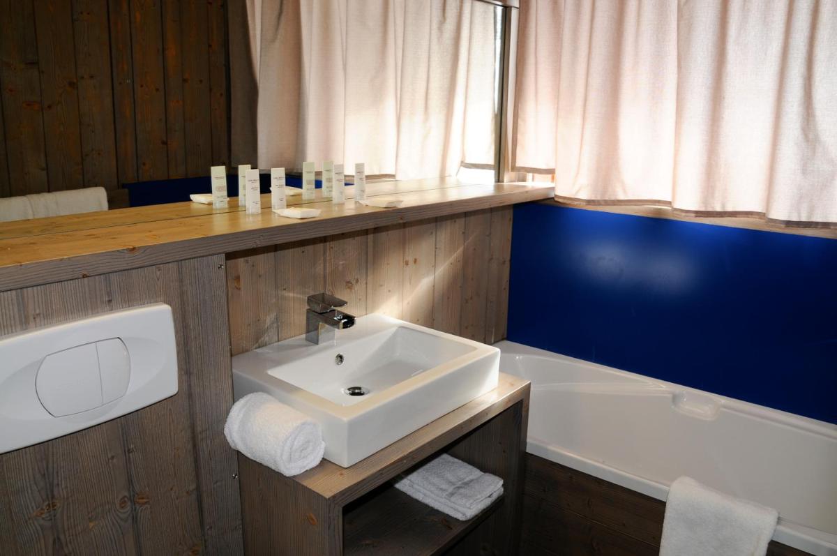 une salle de bain avec un lavabo et une baignoire dans l'établissement Hôtel Arcadien, à Arc 1600