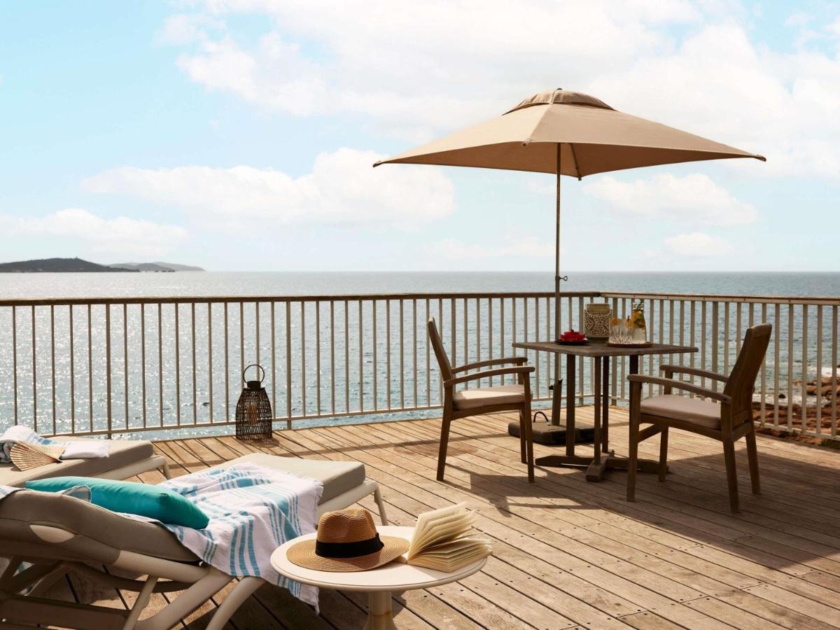une terrasse avec une table et un parasol dans l'établissement Sofitel Golfe d'Ajaccio Thalassa Sea & Spa, à Ajaccio