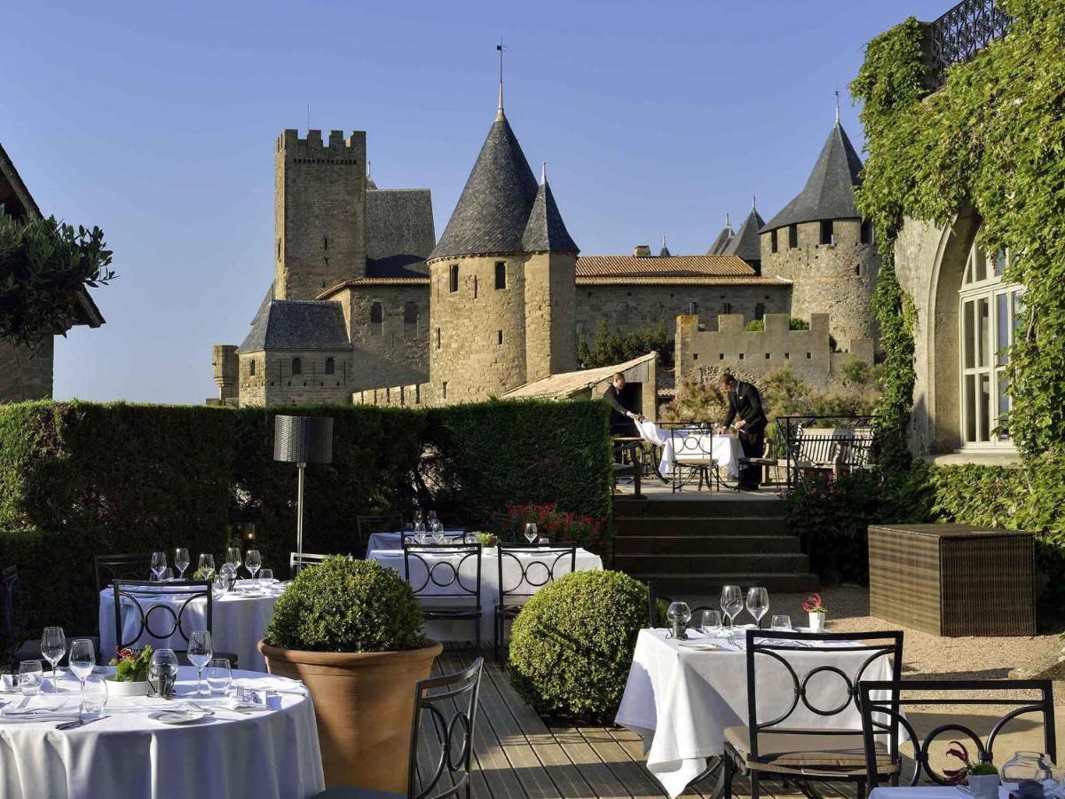 un patio avec des tables et des chaises devant un château dans l'établissement Hotel de la Cité Carcassonne - MGallery Collection, à Carcassonne
