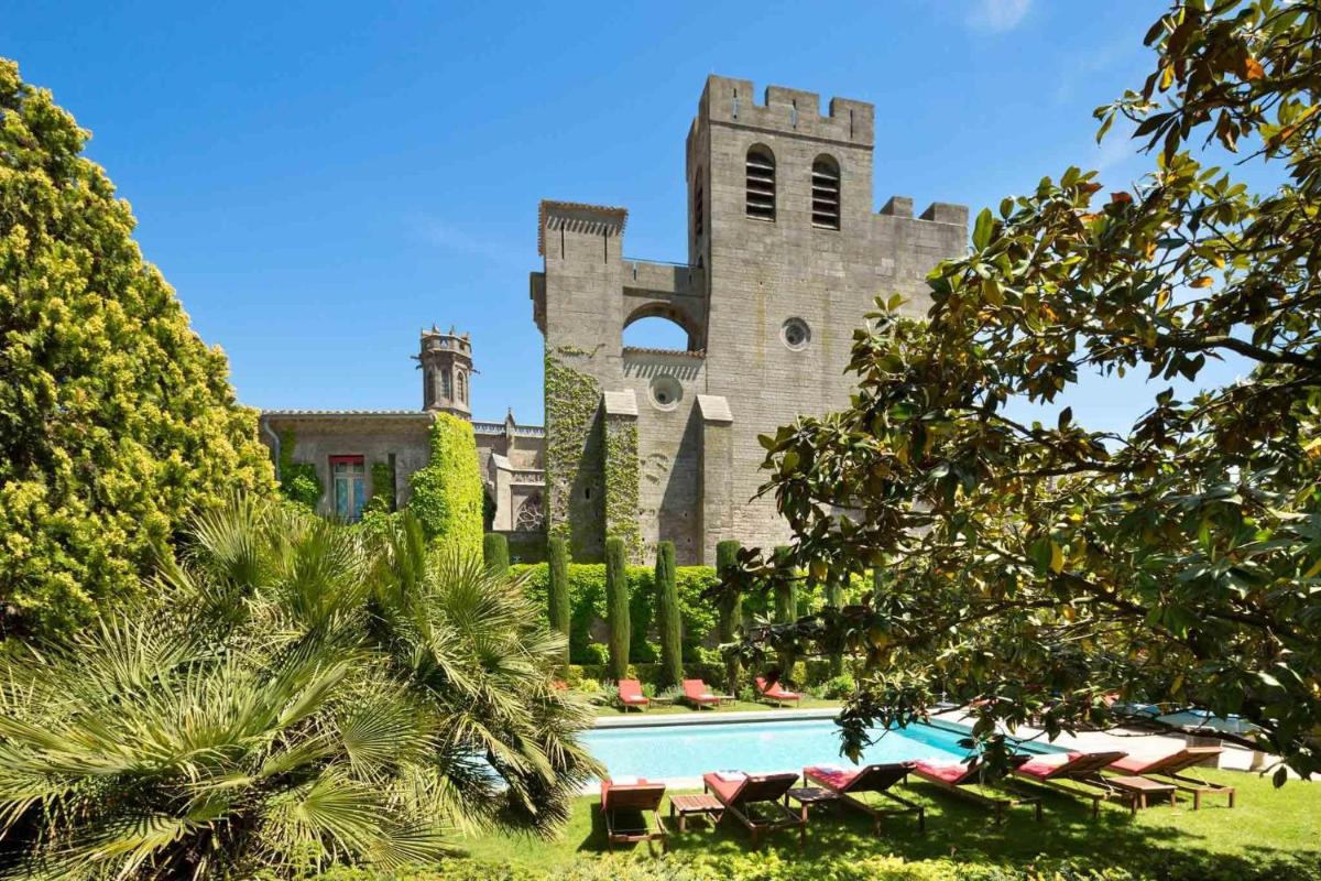 un château avec une piscine devant un bâtiment dans l'établissement Hotel de la Cité Carcassonne - MGallery Collection, à Carcassonne