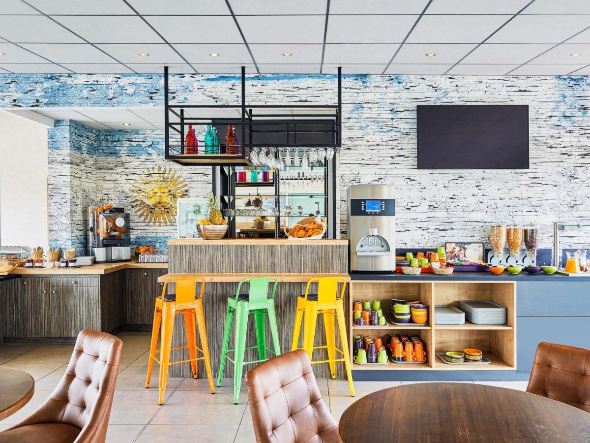 un restaurant avec des tabourets colorés et un comptoir dans l'établissement Ibis Styles Hyères Rooftop & Spa, à Hyères