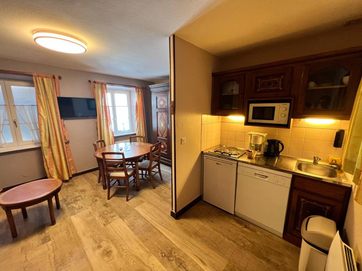 une petite cuisine et une salle à manger avec une table dans l'établissement La Cour du Bailli Suites & Spa, à Bergheim