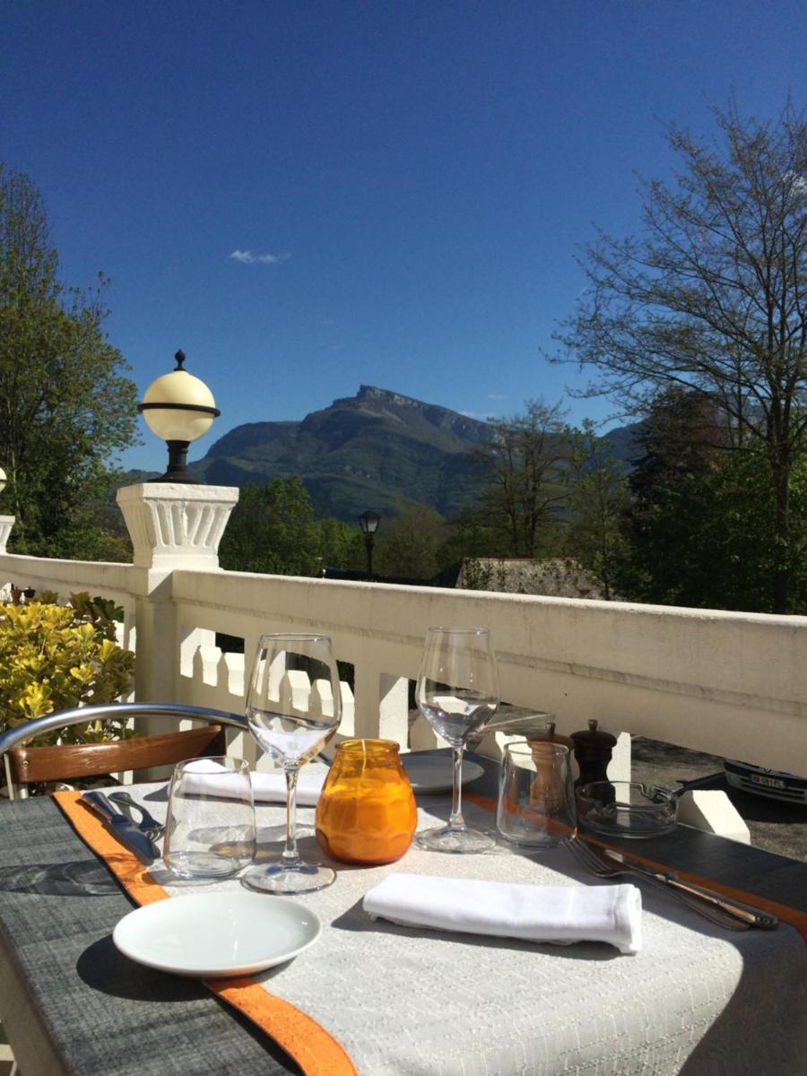 une table avec des chaises et des verres à vin sur un balcon dans l'établissement Hôtel Spa & Restaurant Ô Pervenches, à Chambéry