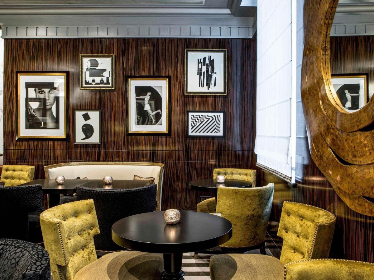 un restaurant avec des tables et des chaises et des tableaux aux murs dans l'établissement Sofitel Paris Le Faubourg, à Paris 148 autres photos