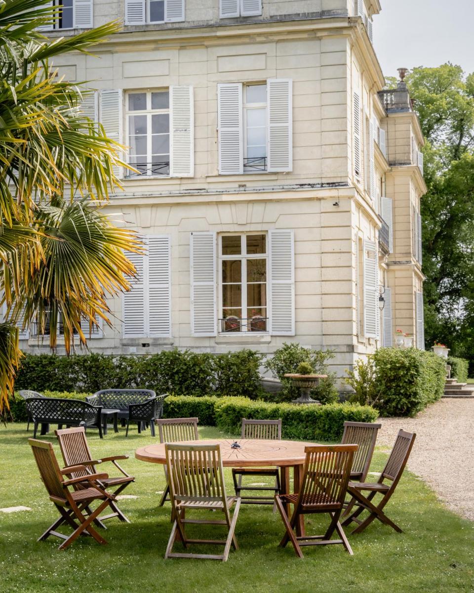 un groupe de chaises et une table devant une maison dans l'établissement Chateau du boulay morin, à Le Boulay-Morin
