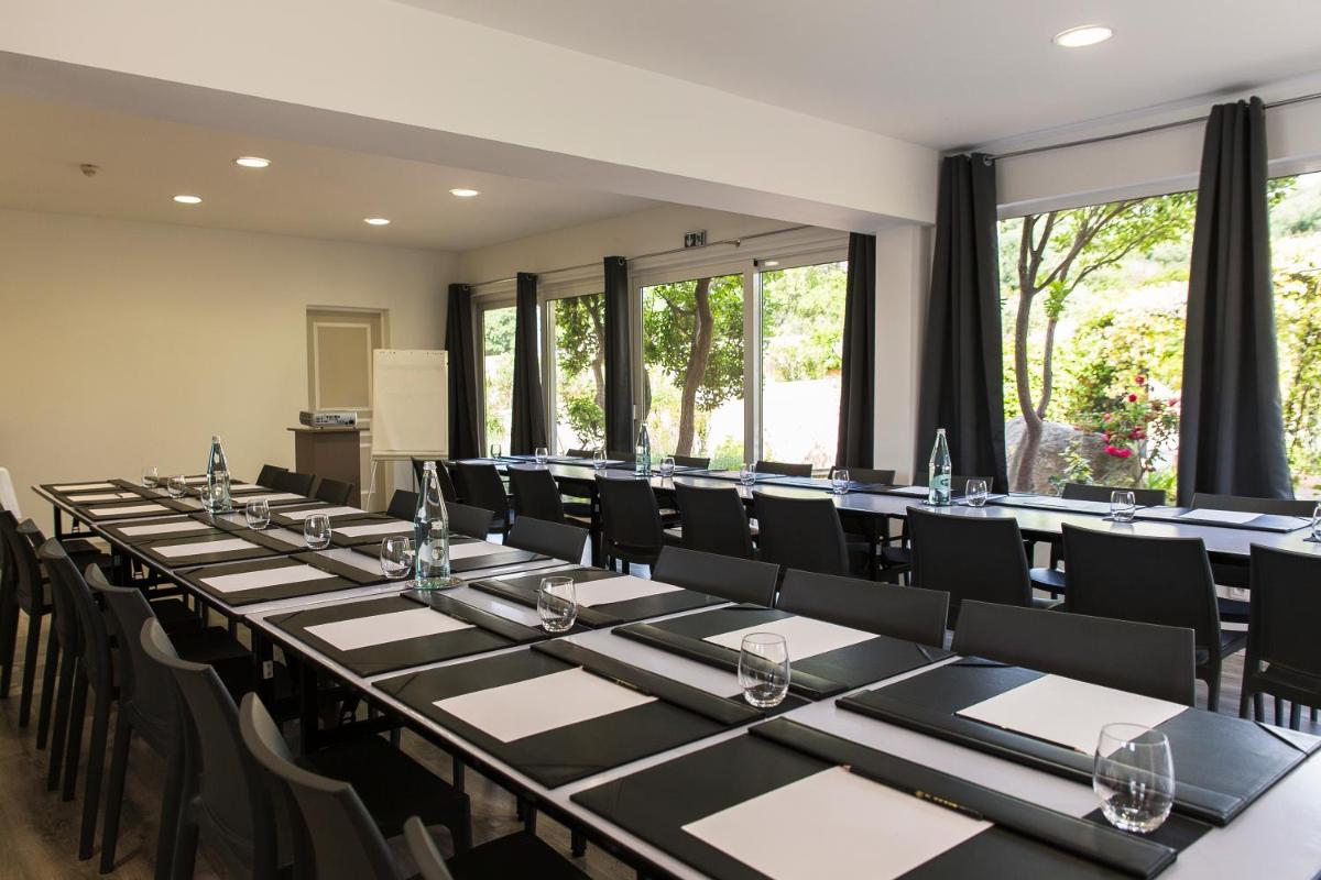 une rangée de tables et de chaises dans une pièce avec des fenêtres dans l'établissement Hôtel Le Roi Théodore & Spa, à Porto-Vecchio 68 autres photos