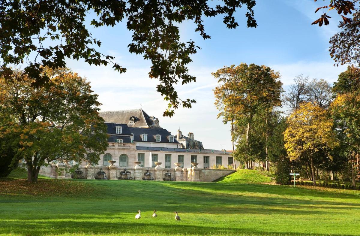 une maison sur une pelouse avec des gens qui marchent devant dans l'établissement Auberge du Jeu de Paume, à Chantilly