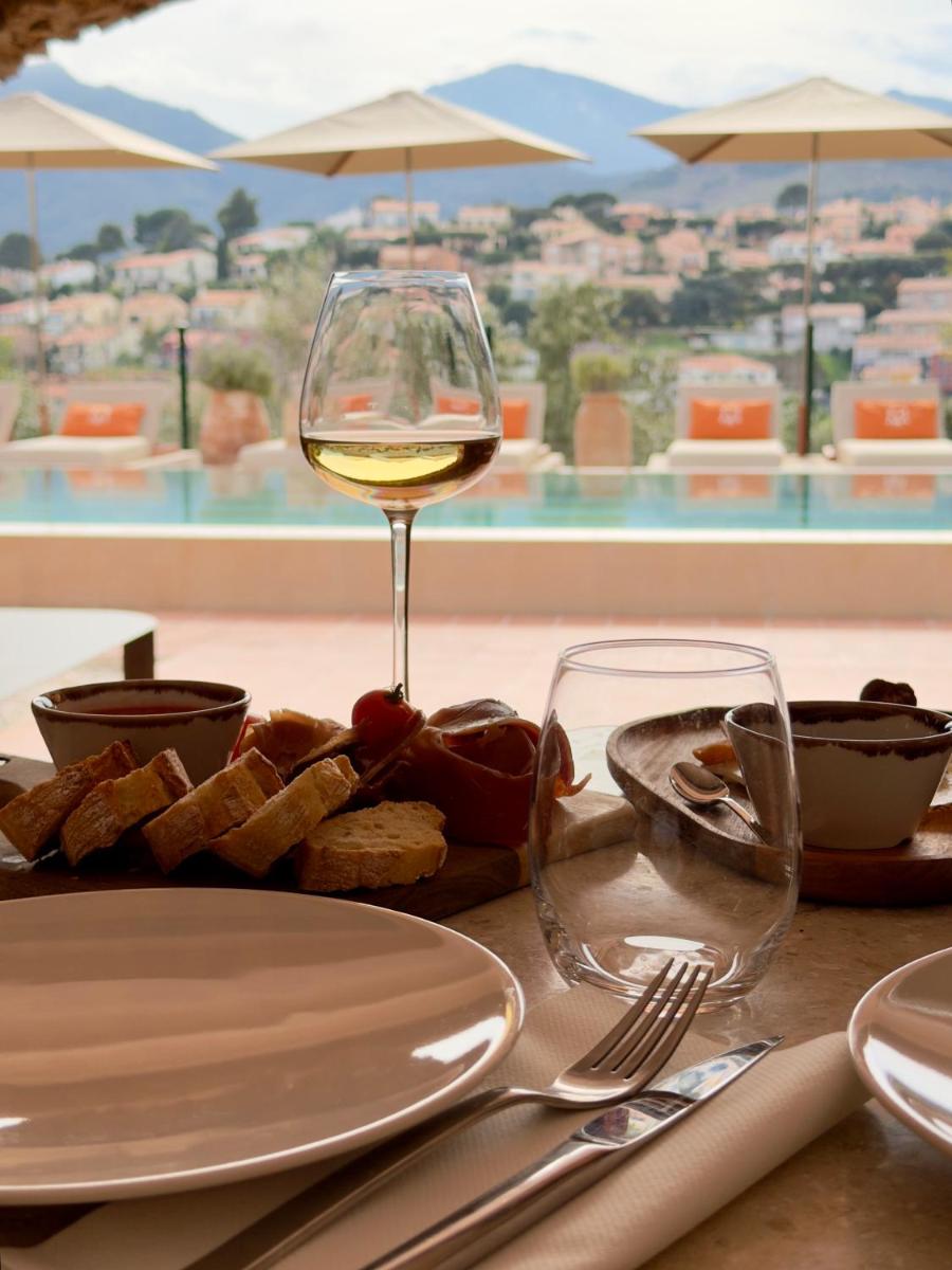 une table avec un verre de vin et une assiette de nourriture dans l'établissement Maison Nova - Boutique Hôtel & Spa, à Collioure