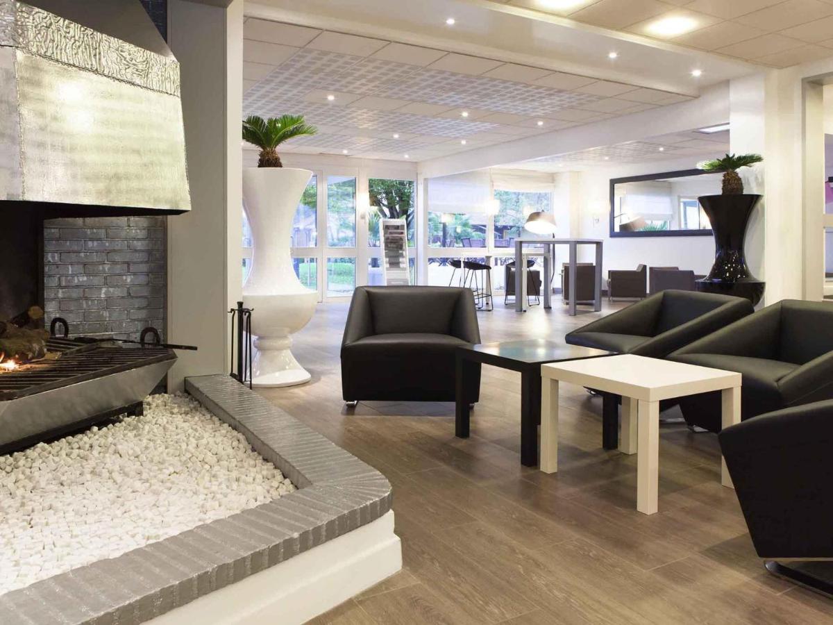un salon avec un canapé et une cheminée dans l'établissement Novotel Fontainebleau Ury, à Ury