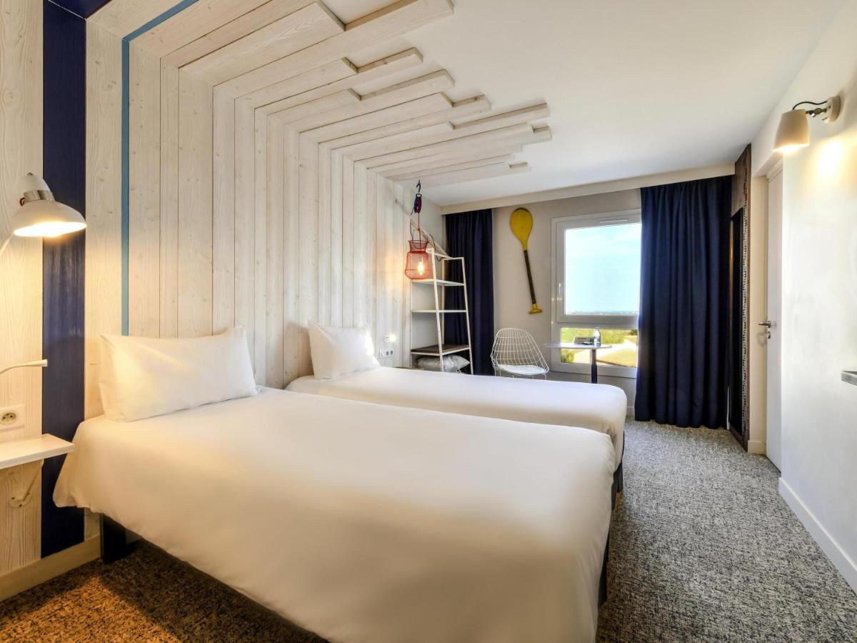 une chambre d'hôtel avec deux lits et une fenêtre dans l'établissement ibis styles La Rochelle Thalasso Chatelaillon, à Châtelaillon-Plage