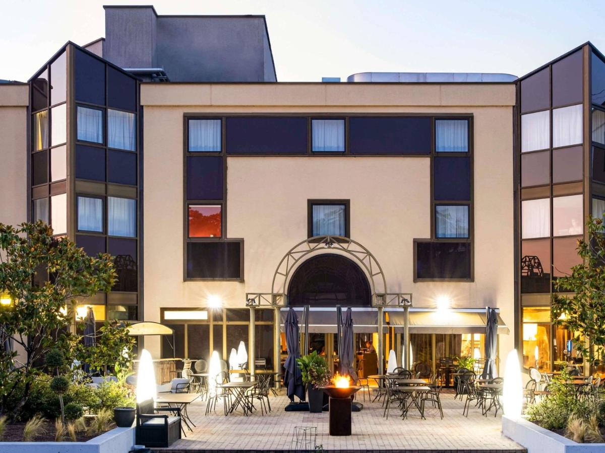 un bâtiment avec des tables et des chaises devant dans l'établissement Mercure Tours Sud, à Joué-lès-Tours