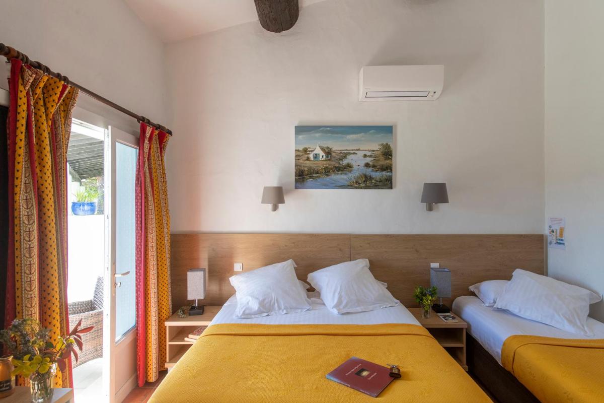 une chambre d'hôtel avec deux lits et une fenêtre dans l'établissement Mas de la Grenouillère Hôtel et Centre équestre en pleine nature, à Saintes-Maries-de-la-Mer