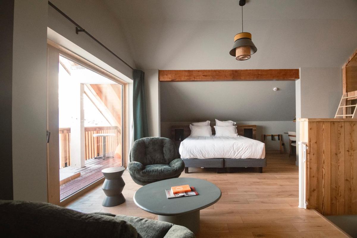 une chambre avec un lit, une chaise et une table dans l'établissement Les Cèdres - Hôtel - Restaurants - Spa, à Saint-Sorlin-dʼArves