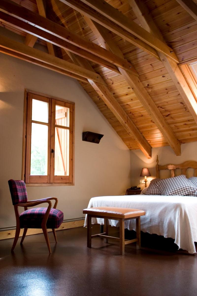 Un dormitorio con una cama, una silla y una mesa. en Hotel Caldas, en Caldes de Boí