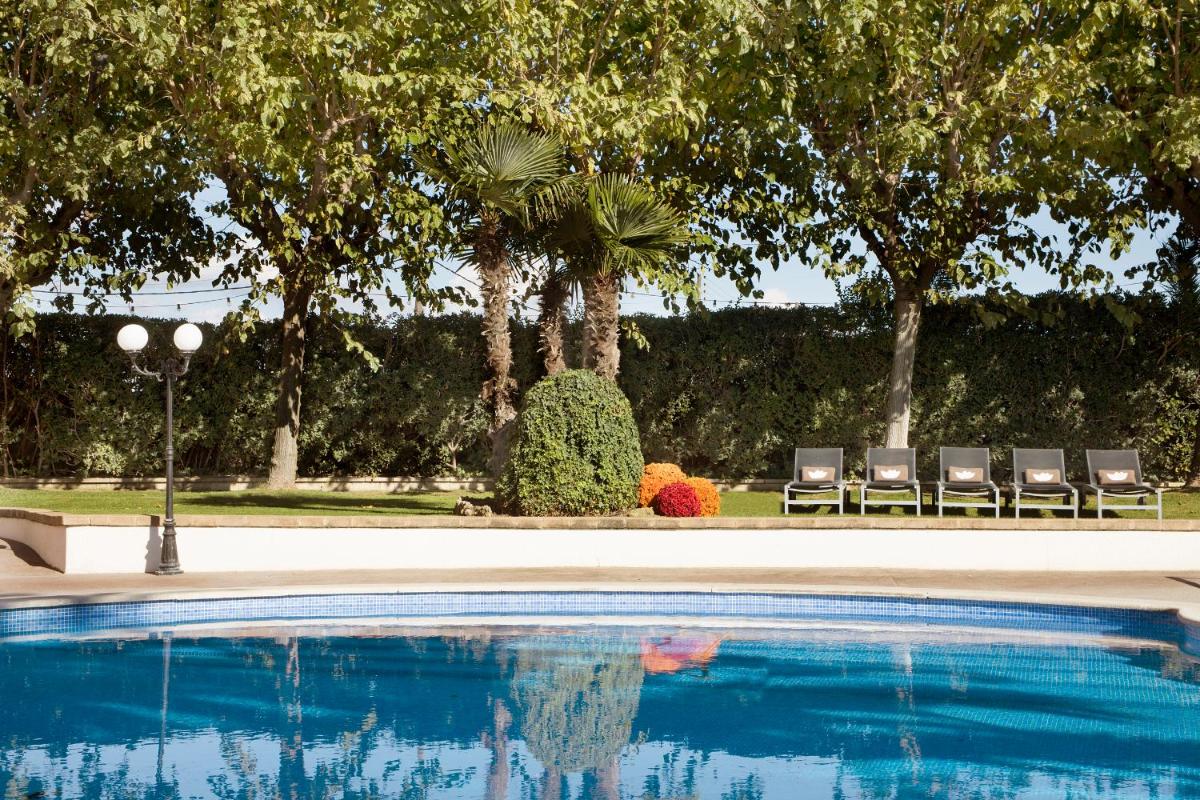 una piscina con dos sillas y palmeras en Luna Club Hotel Yoga & Spa 4Sup, en Malgrat de Mar