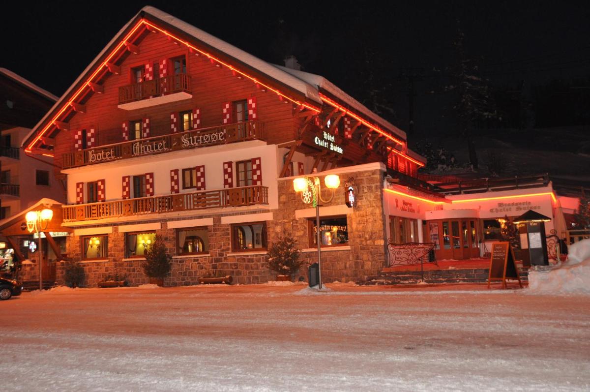 un grand bâtiment en bois avec des lumières allumées la nuit dans l'établissement Le Chalet Suisse, à Valberg