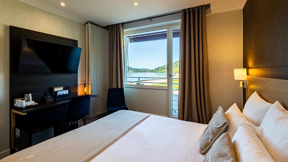 une chambre d'hôtel avec un grand lit et une fenêtre dans l'établissement Hôtel Beau Rivage, à Gérardmer 93 autres photos