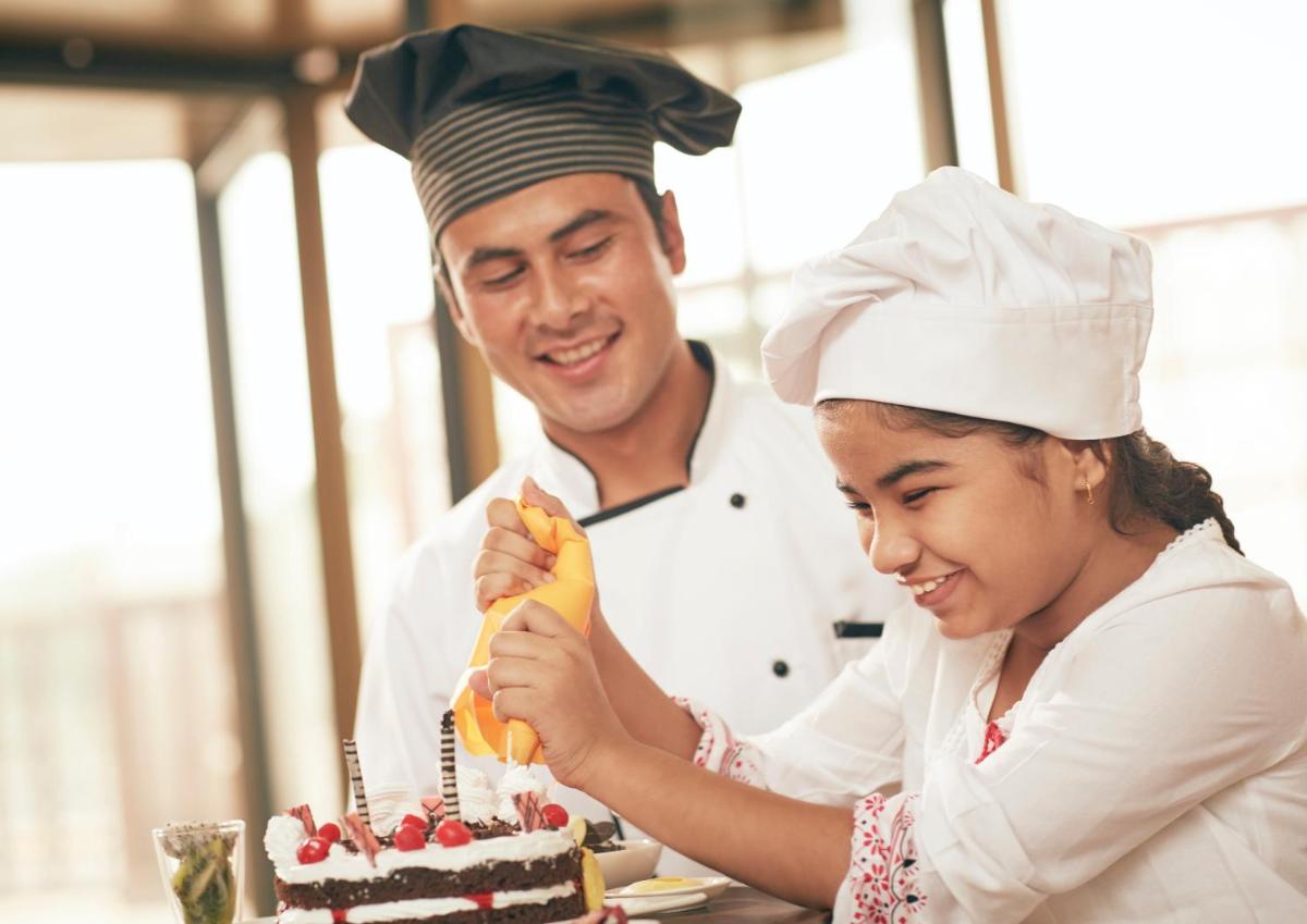 a man and a girl lighting candles on a cake at Taj Swarna, Amritsar in Amritsar