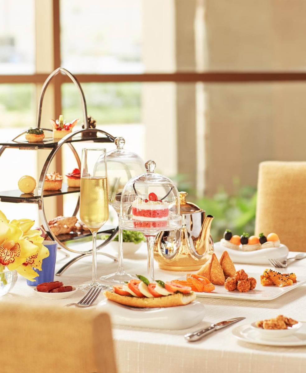 a table topped with plates of food and glasses of wine at Taj Swarna, Amritsar in Amritsar