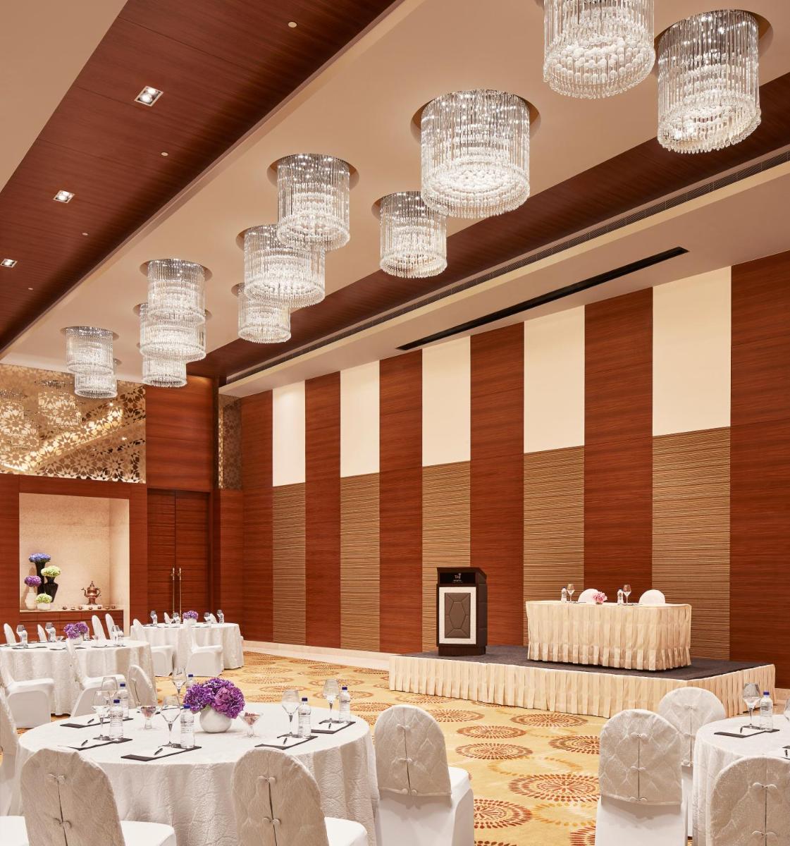 a banquet hall with white tables and chairs and chandeliers at Taj Swarna, Amritsar in Amritsar