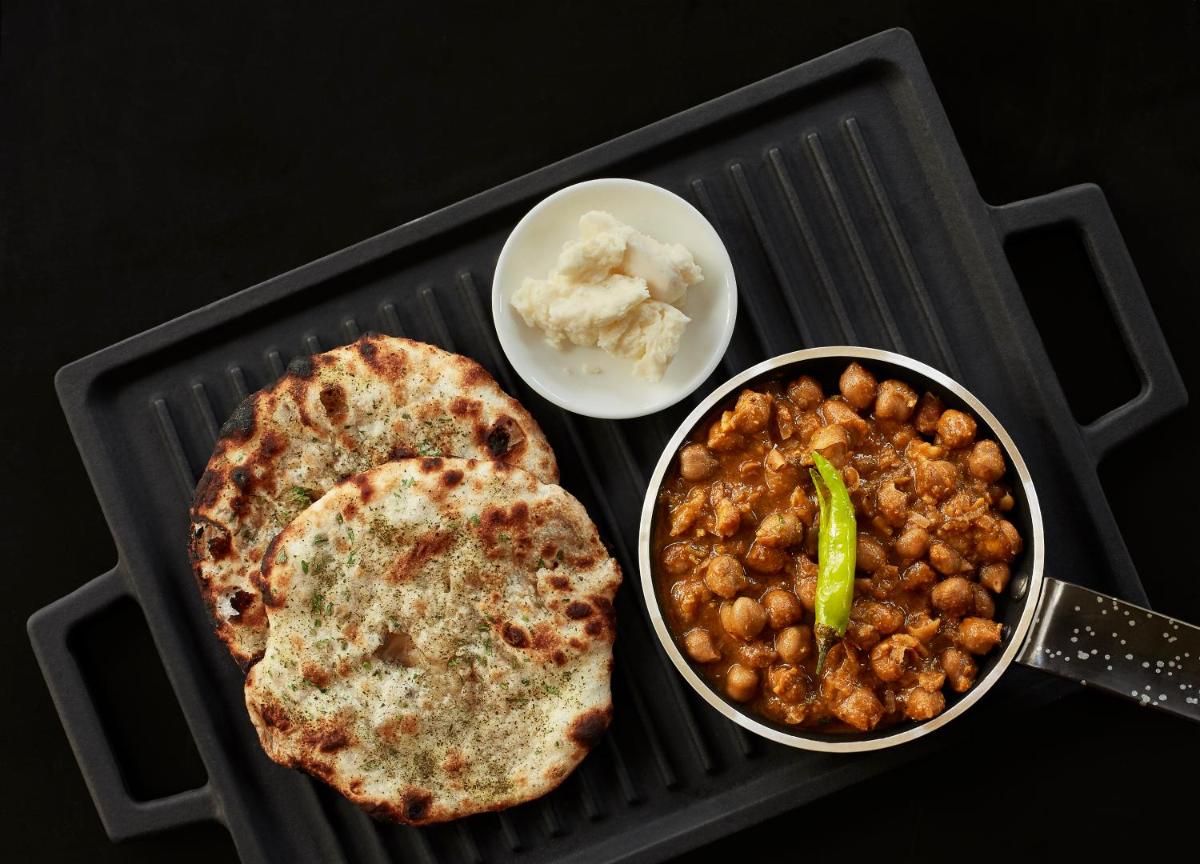 a grill with a plate of chickpeas and a bowl of food at Taj Swarna, Amritsar in Amritsar