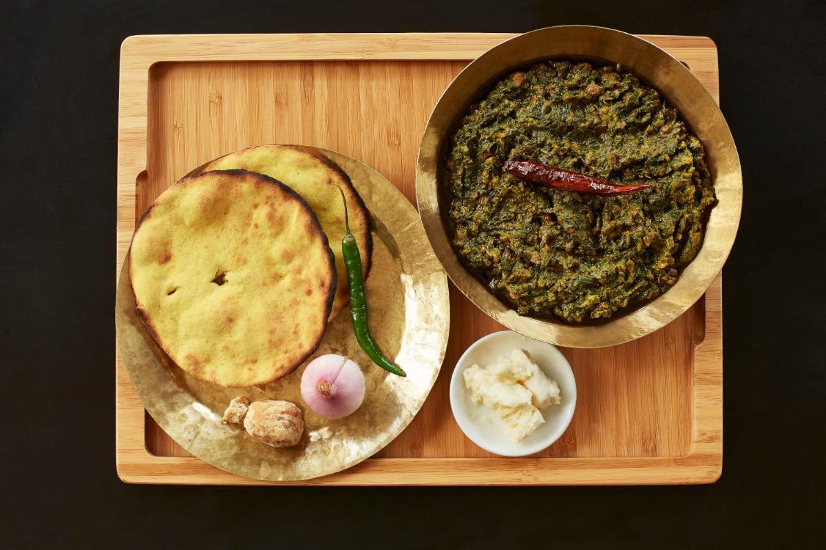 a wooden tray with two pizzas and a plate of food at Taj Swarna, Amritsar in Amritsar