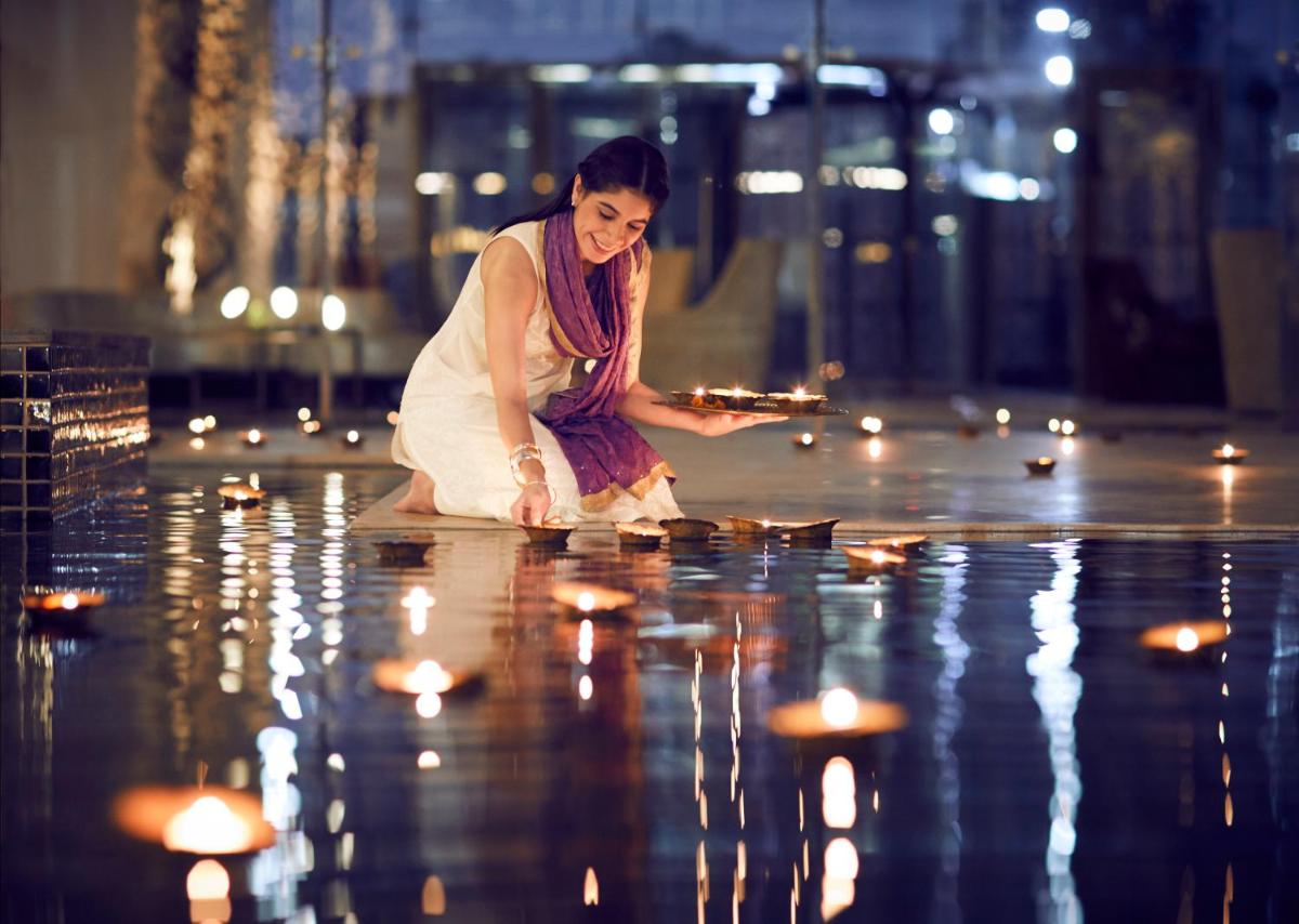 a woman sitting on the floor with candles in the water at Taj Swarna, Amritsar in Amritsar