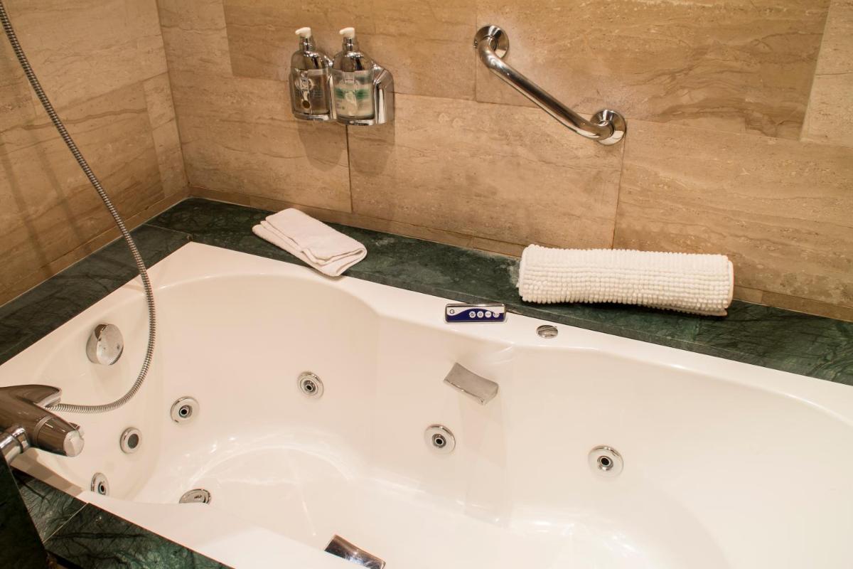 Una bañera blanca en un baño con ducha. en La Violeta HOTEL SPA & CHILL OUT, en Castelltersol