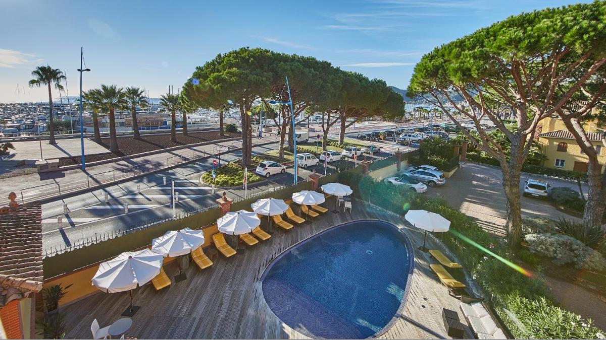 - une vue sur la piscine avec parasols et un parking dans l'établissement Ermitage de l'Oasis & Spa - Cannes Mandelieu, à Mandelieu-la-Napoule