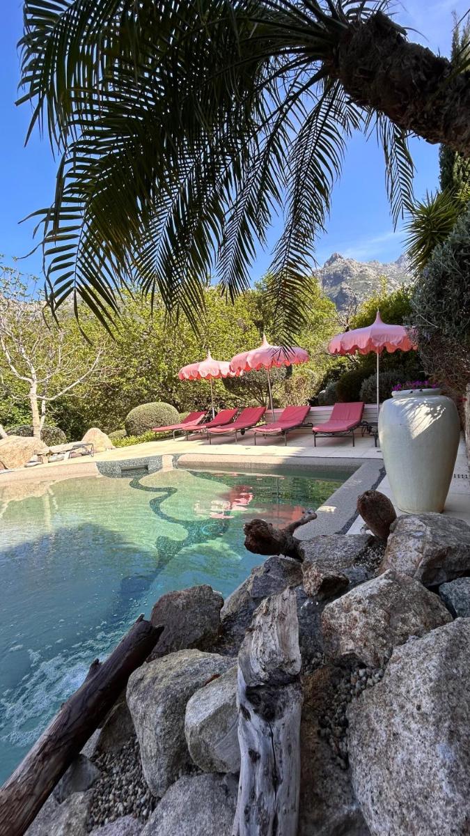 une piscine avec des chaises et des parasols rouges dans l'établissement Cas'Anna Lidia - Hôtel De Charme, à Feliceto