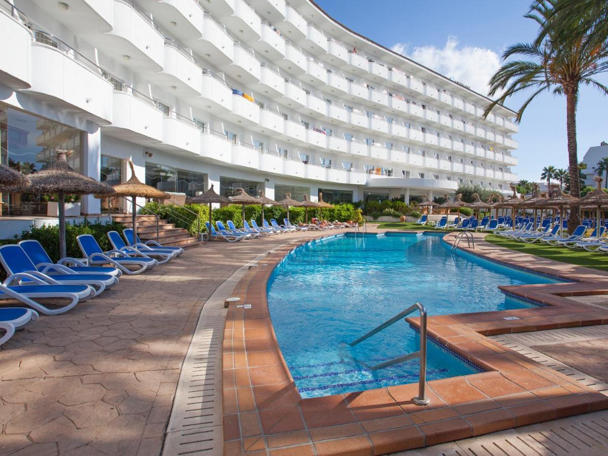 Un hotel con piscina y sillas y un edificio. en Grupotel Maritimo, en Puerto de Alcudia