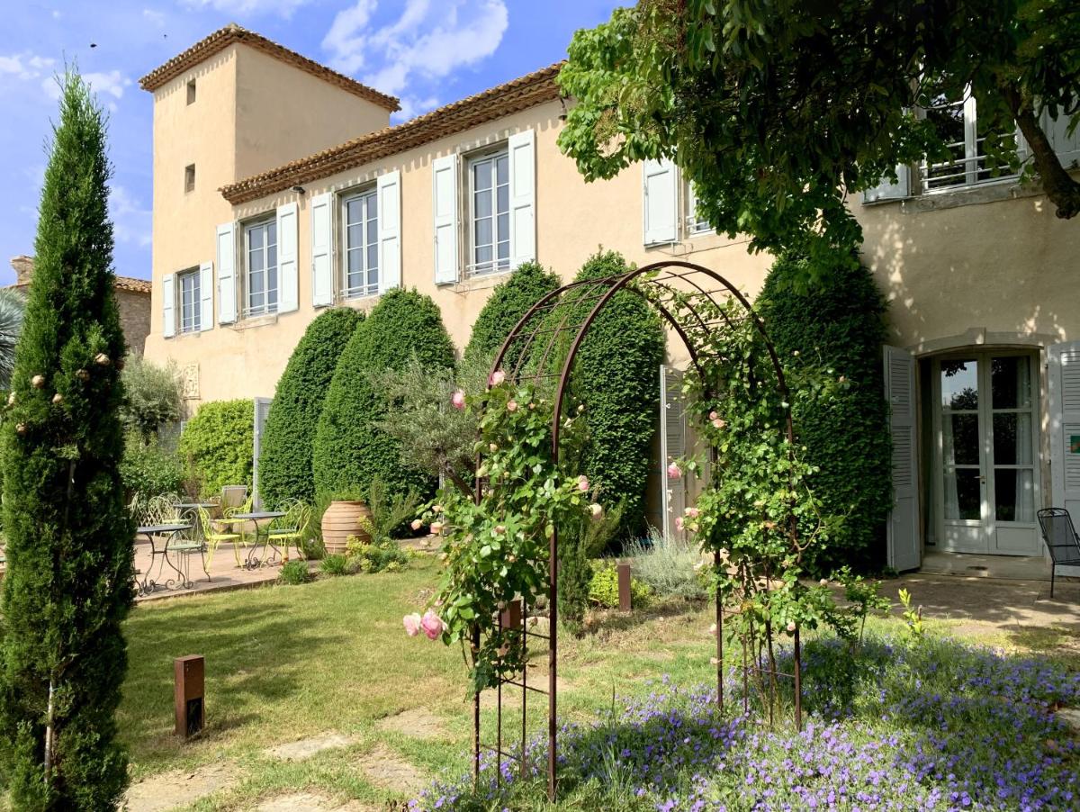 un jardin devant une maison avec des roses dans l'établissement Château De Siran - Hôtel & Spa, à Siran