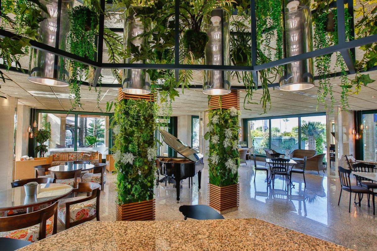 Un restaurante con mesas, sillas y plantas. en Hotel La Laguna Spa & Golf, en Torrevieja