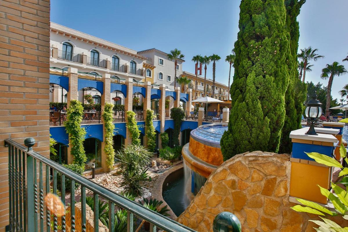 Un complejo con una fuente, árboles y edificios. en Hotel La Laguna Spa & Golf, en Torrevieja