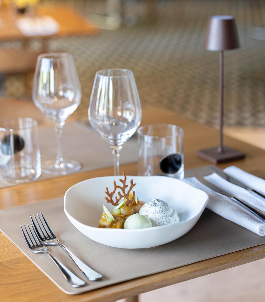 un bol blanc de nourriture sur une table avec des verres à vin dans l'établissement Grand Hotel Du Golfe - Spa & Restaurant, à Collioure