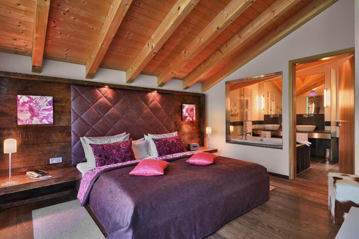 ein Schlafzimmer mit einem großen Bett mit rosa Kissen in der Unterkunft Hotel Maximilian in Oberammergau