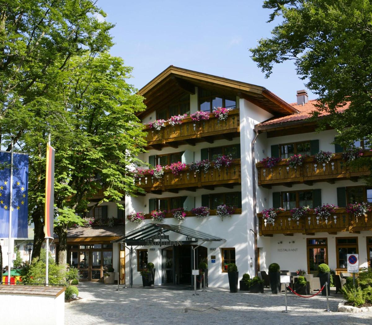 ein Hotel mit Blumenkästen auf den Balkonen in der Unterkunft Hotel Maximilian in Oberammergau
