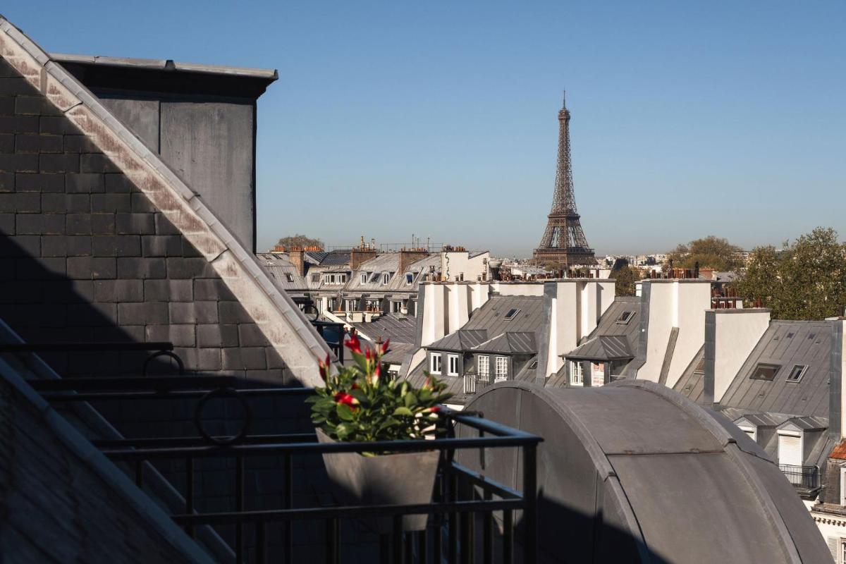 un pot de fleurs sur un balcon avec la tour Eiffel dans l'établissement Hotel Montalembert, à Paris