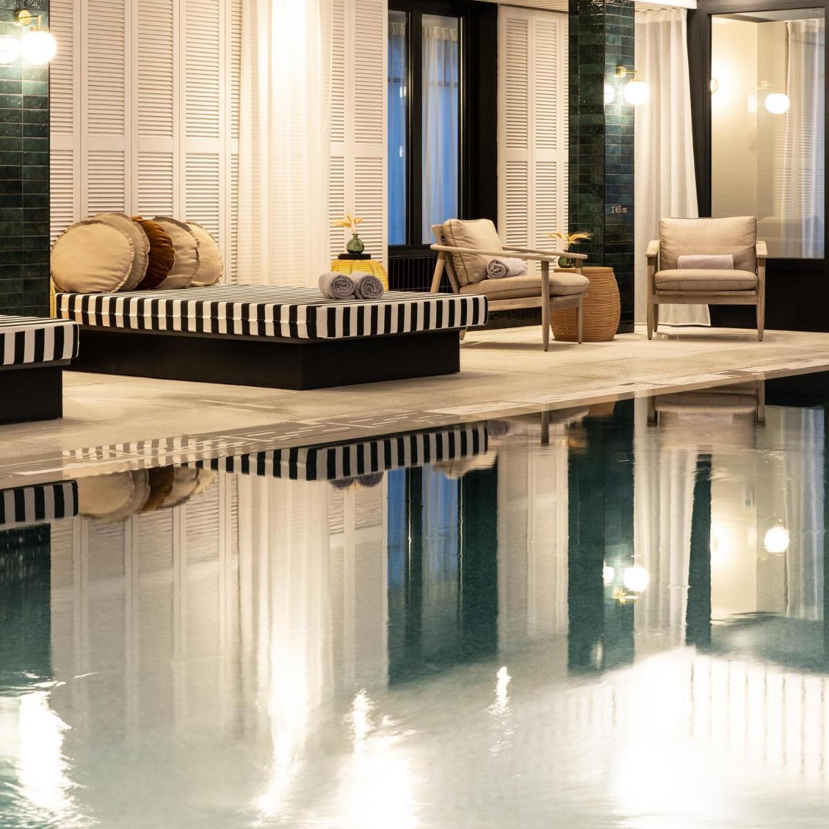 une piscine avec un lit et des chaises à côté dans l'établissement Le Celtique & Spa, à Carnac