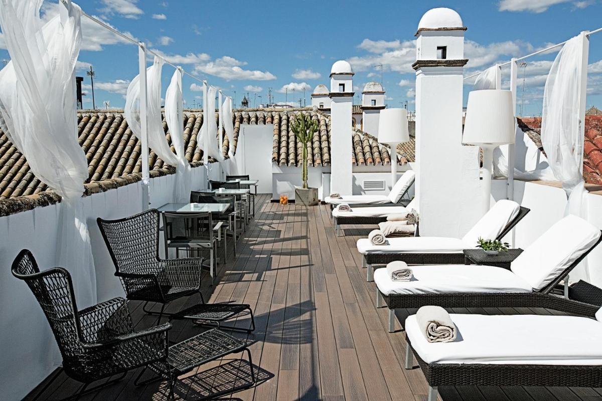 Un patio con sillas y mesas en un tejado. en Hospes Las Casas del Rey de Baeza, a Member of Design Hotels, en Sevilla