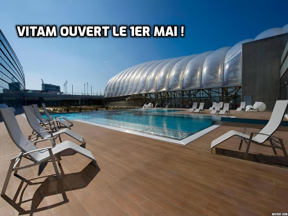 une piscine avec des chaises devant un bâtiment dans l'établissement ibis Styles Saint Julien en Genevois Vitam, à Neydens
