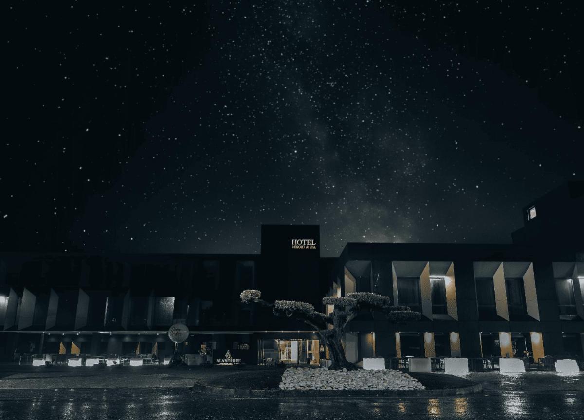 um prédio com uma árvore na frente à noite em Alambique - Hotel Resort & Spa no Fundão