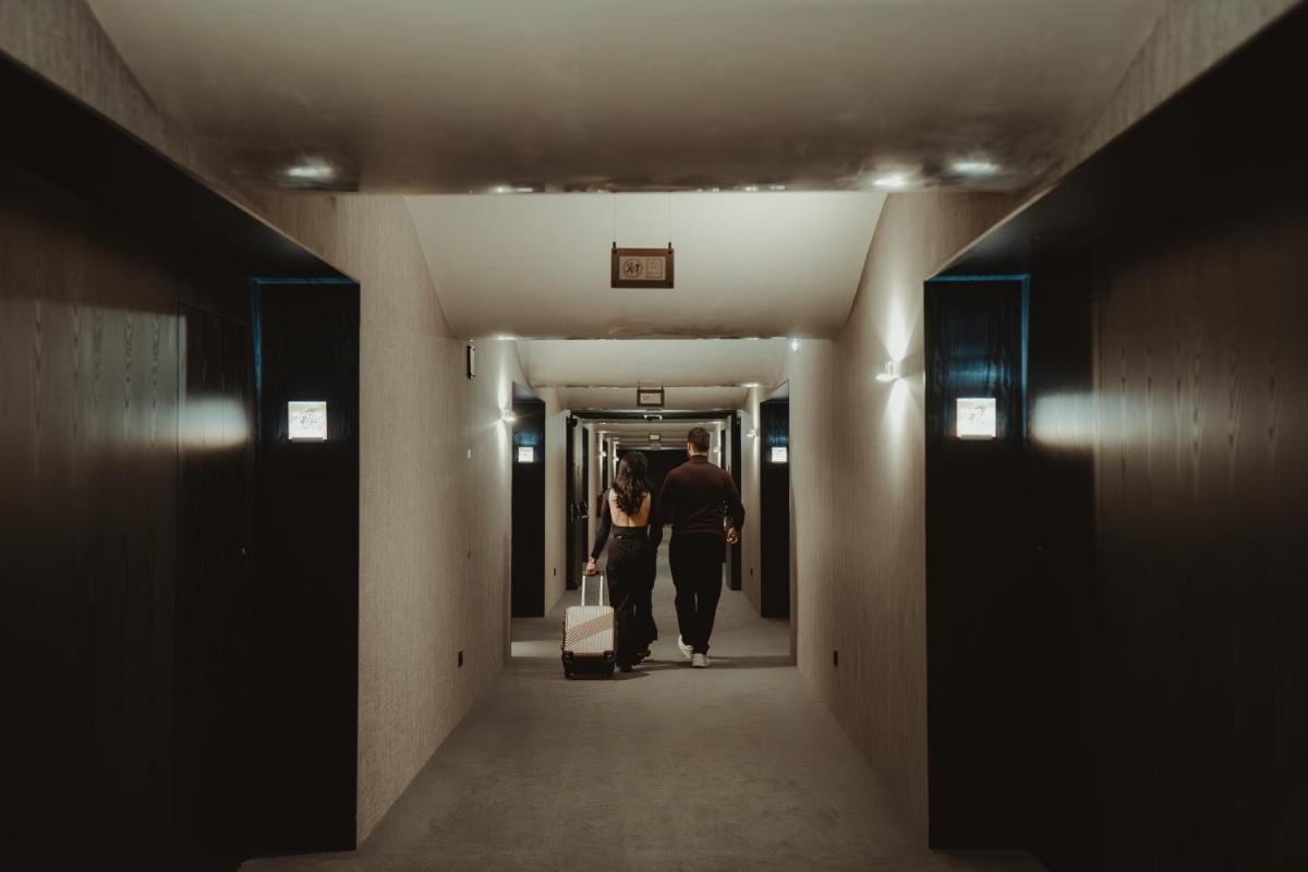 um homem e uma mulher caminhando por um corredor com bagagem em Alambique - Hotel Resort & Spa no Fundão mais 130 fotografias