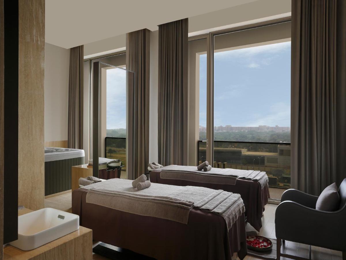 a hotel room with two beds and a window at Roseate House New Delhi in New Delhi a hotel room with two beds and a window at Roseate House New Delhi in New Delhi