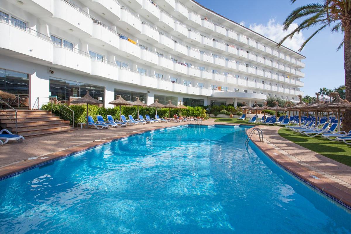 Un gran hotel con una gran piscina y sillas. en Grupotel Maritimo, en Puerto de Alcudia