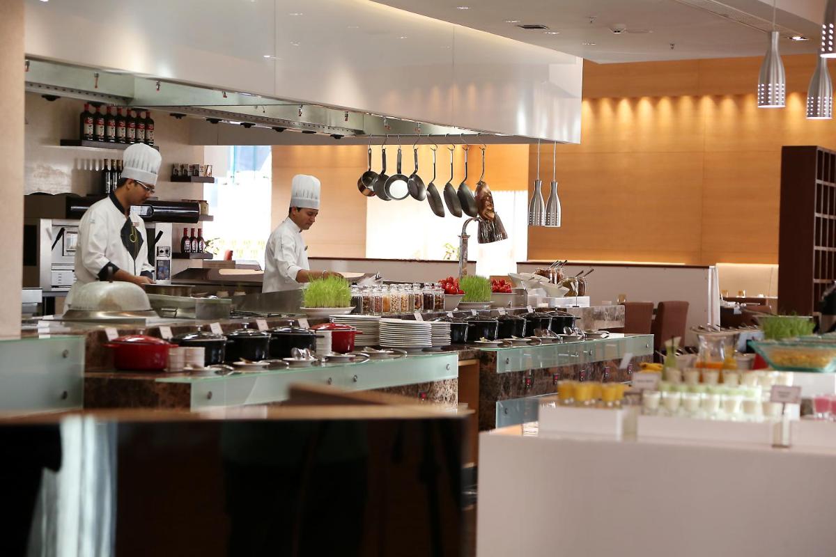 two chefs preparing food in a restaurant kitchen at Novotel Pune Viman Nagar Road in Pune