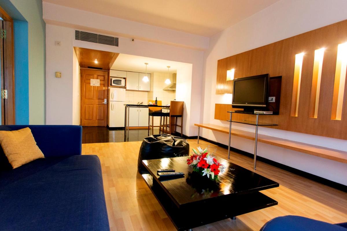 a living room with a blue couch and a coffee table at Hotel Royal Orchid Bangalore in Bengaluru