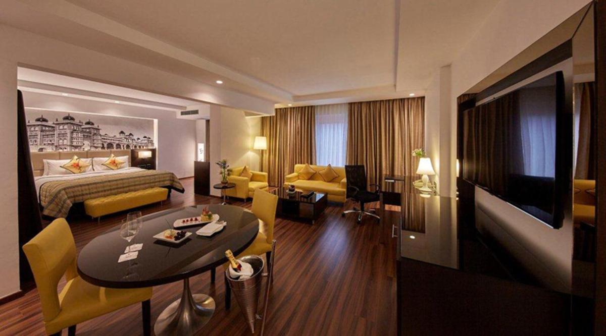 a hotel room with a bed and a living room at Hotel Royal Orchid Bangalore in Bengaluru